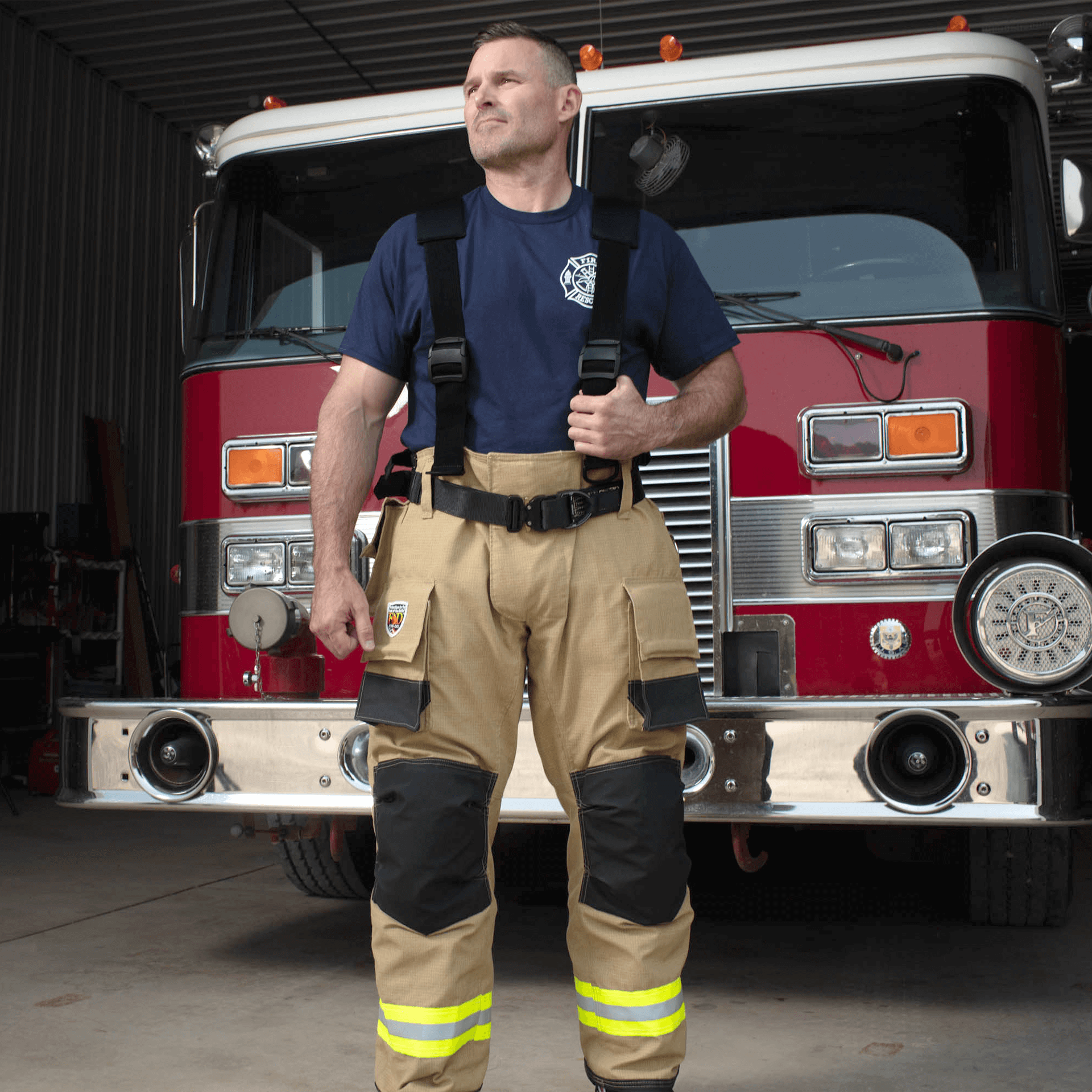 Firefighter in gear in front of fire truck, showing off our flex back suspender